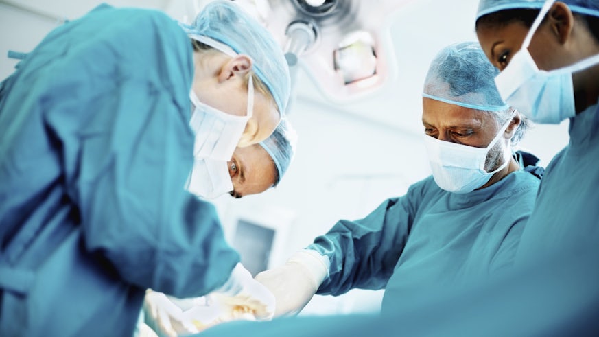 Surgeons in scrubs around operating table 