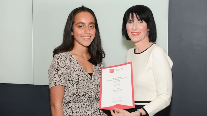 Female student collects award from Dean