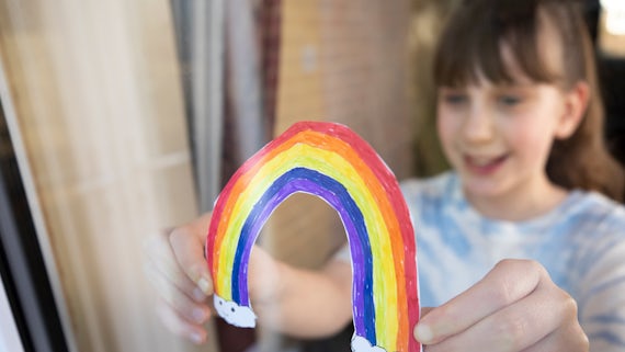 Child sticking rainbow on window stock image