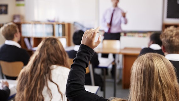Female student raises hand in School classroom