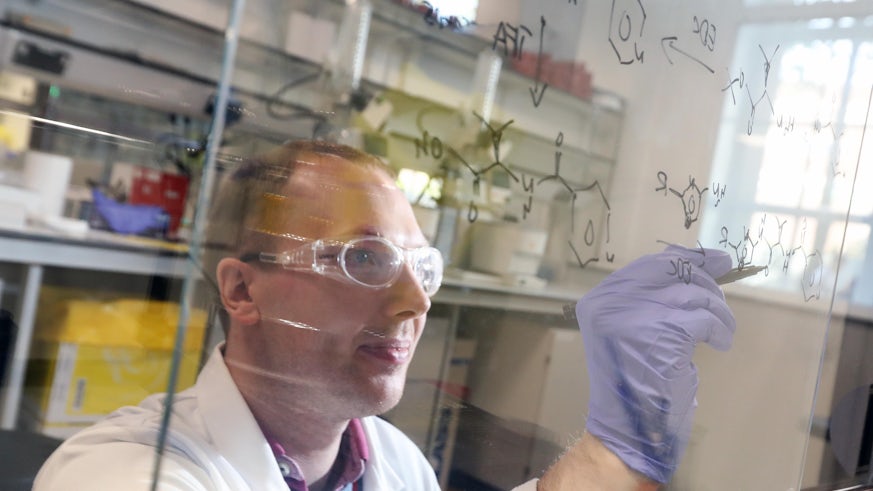 Dr David Foley writes on the glass of a fume hood in the Institute's chemistry lab