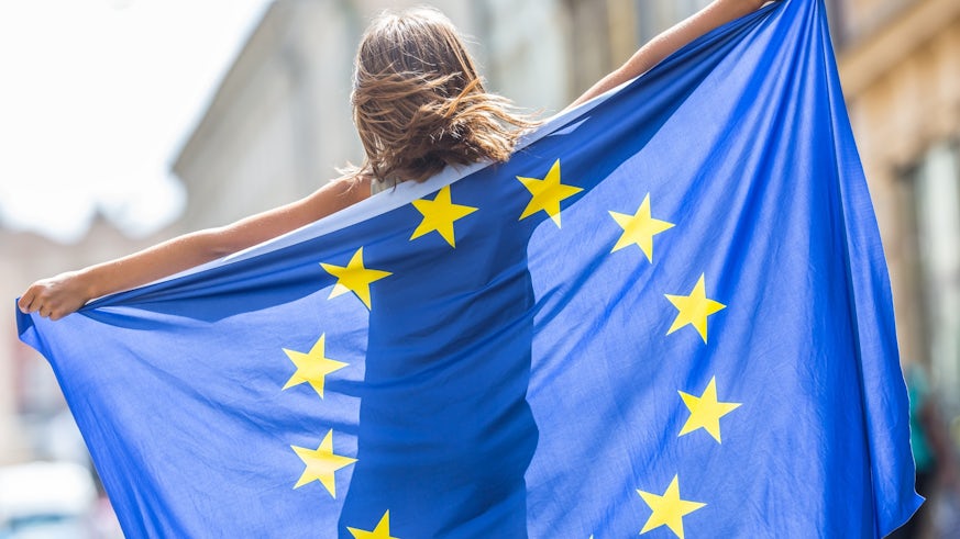 A young girl with the European Union flag draped over her back