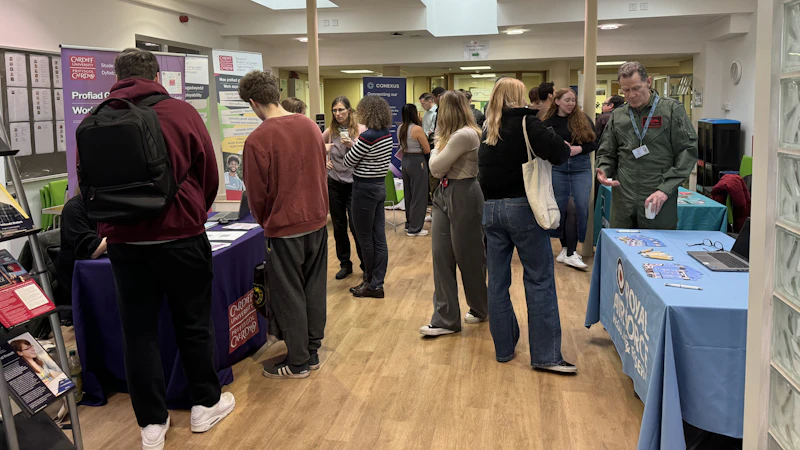 A foyer full of people standing and chatting. Most people are facing away from the camera.