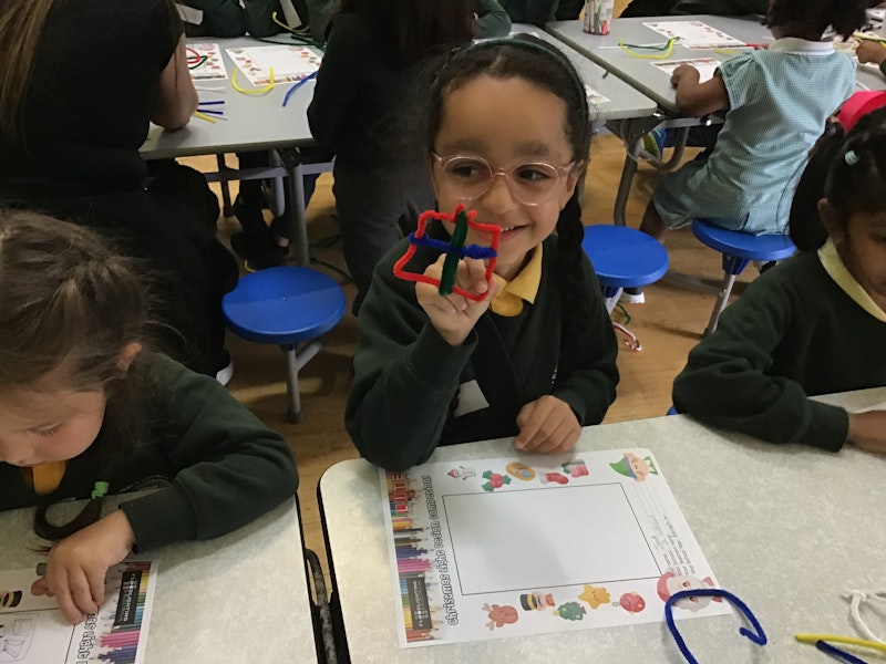 Schoolchildren show designs they have created using pipe cleaners.