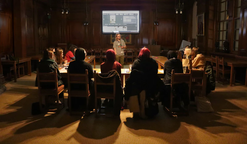 A group of students seated in a wood‑panelled room listening to a Step Up masterclass presentation.