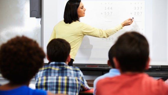 Teacher standing in class with whiteboard