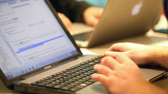 Students typing code into a laptop