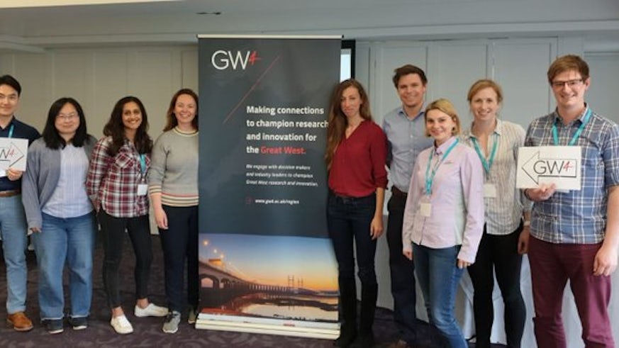 9 young men and women standing by a pull up stand to show their collaboration as a GW4 group.