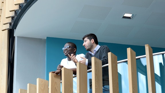Two male postgraduate students leaning over balcony