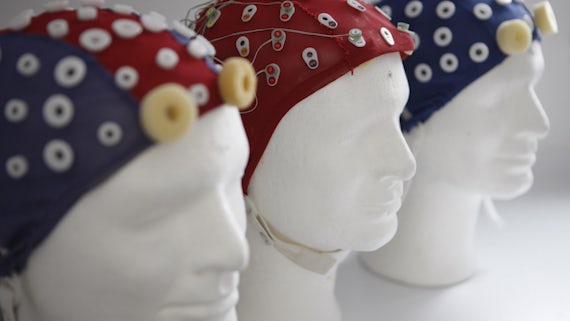 Three white mannequin heads with colourful blue and red EEG caps with places for electrodes to be fitted