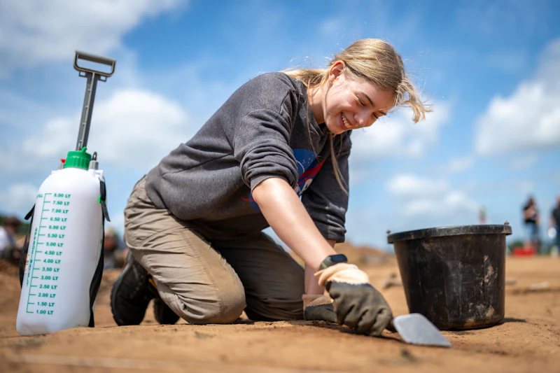 A woman smiles as she works on an archaeological dig site.
