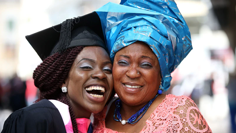 Female student graduating with mother in traditional headdress