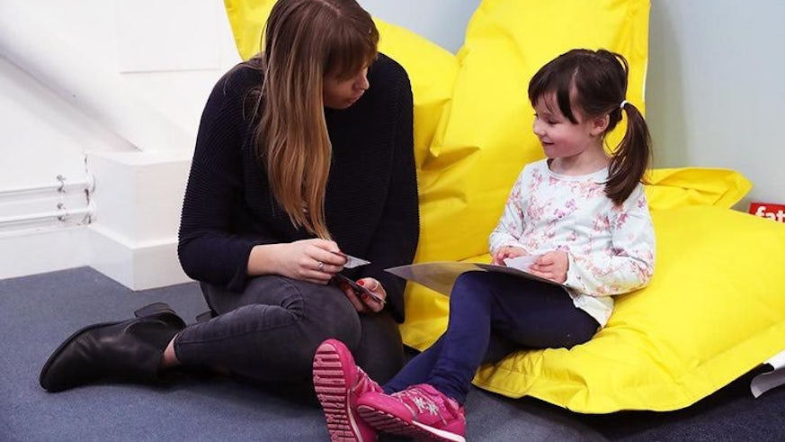 Photograph of child sat on the floor doing an activity with a psychologist