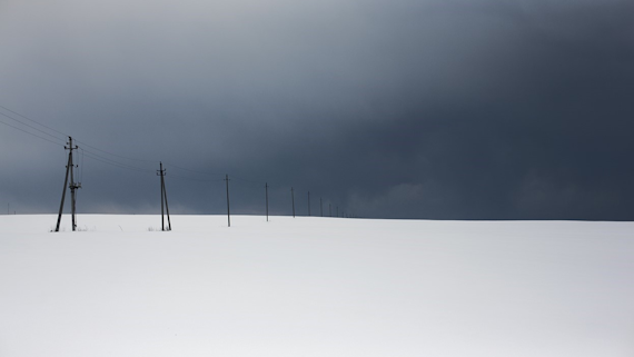 Image of electric pylons in the snow with a dark, cloudy sky
