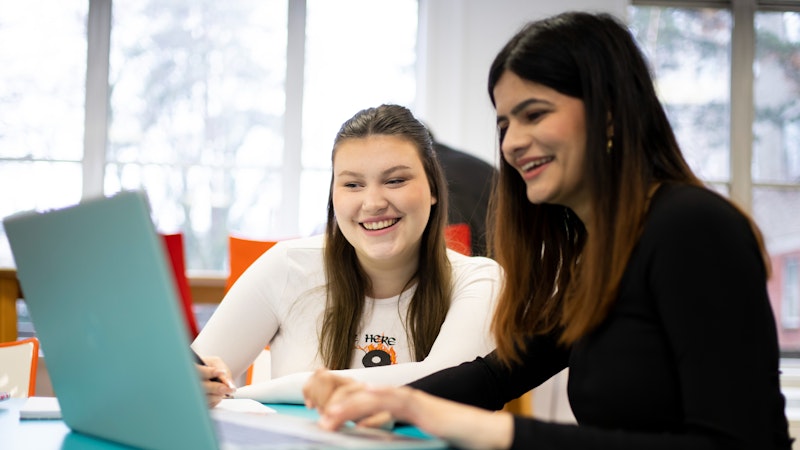 Two female students sat looking at a laptop.