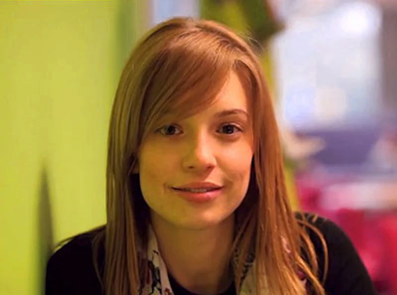 Woman with blond shoulder-length hair smiles into the camera.
