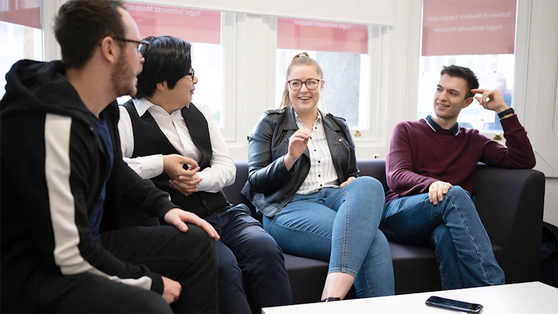 Four students sat on a sofa talking