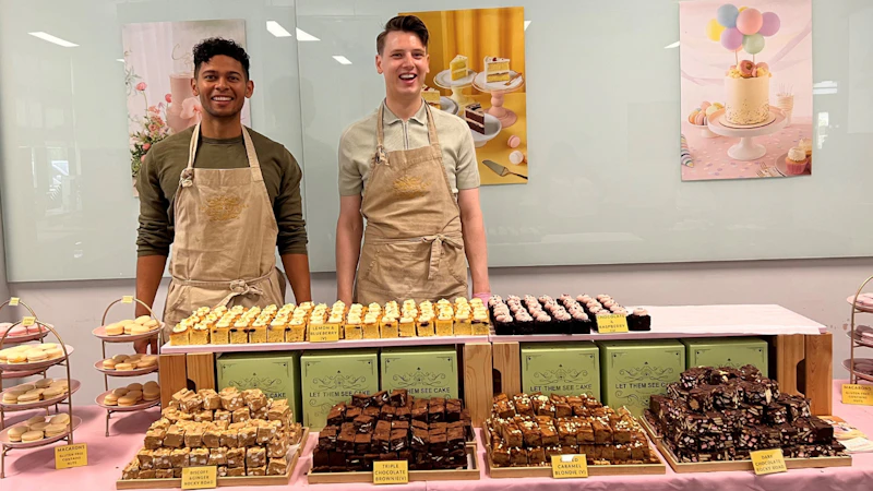 2 people in aprons next to lots of cake