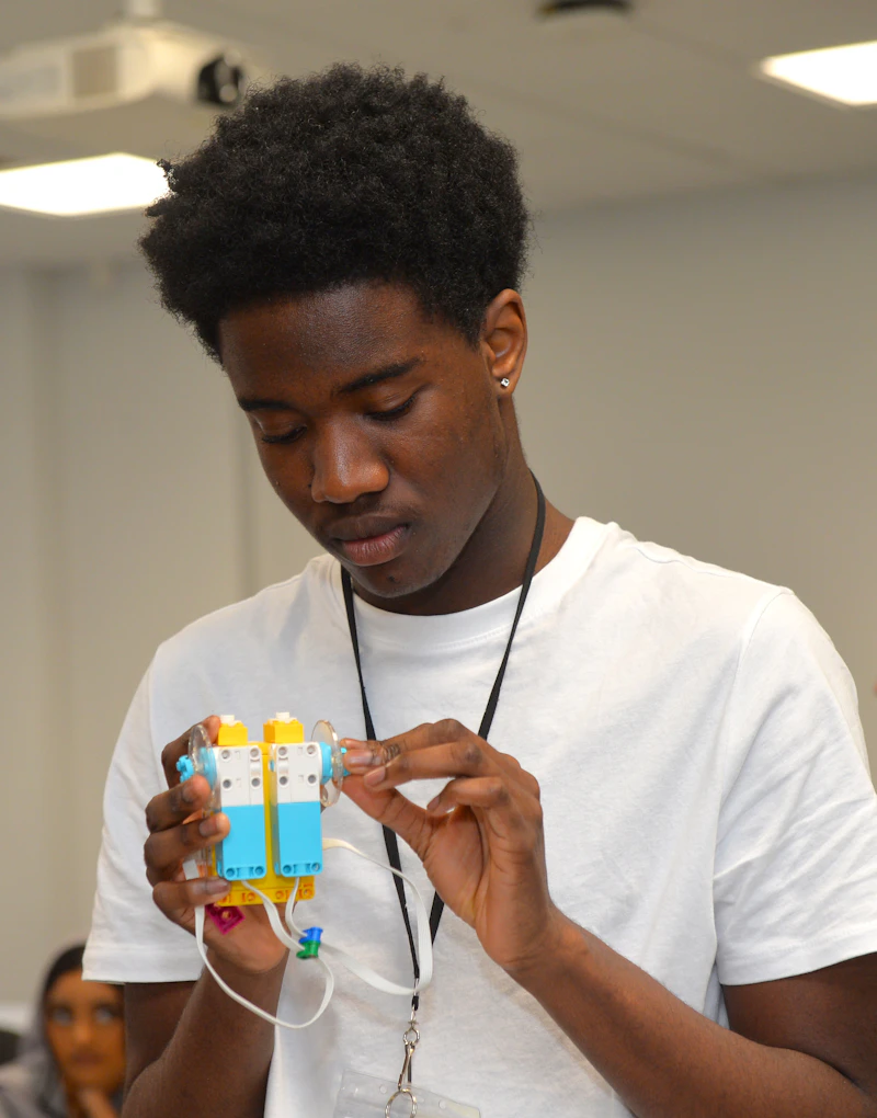 A student assembling a small robotics device during a Step Up practical activity.