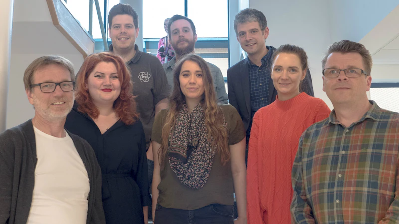 A group of seminar participants stands on a staircase