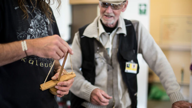 Man demonstrates a hand drill while another looks on