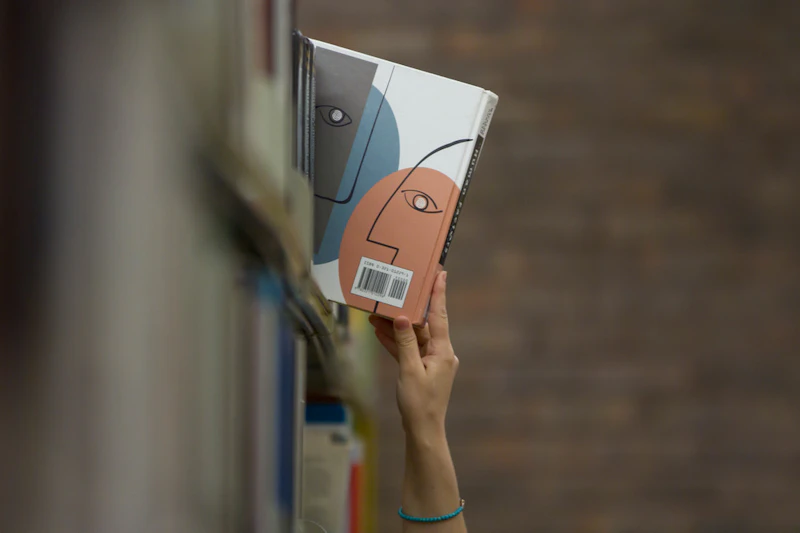 Hand pulling a book out of a bookshelf