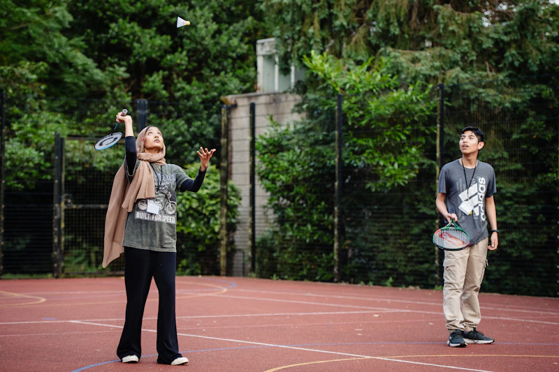 Two students playing badminton on an outdoor court during the Step Up summer school.
