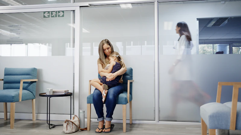Woman is embracing her child as she rests in the chair at medical clinic
