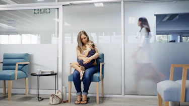 Woman is embracing her child as she rests in the chair at medical clinic